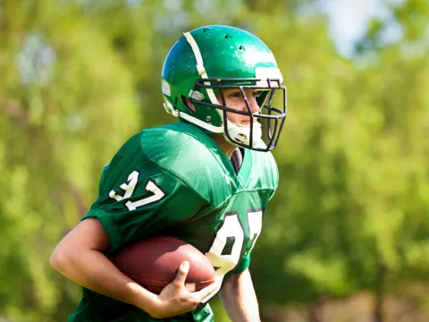 A Teen in Football Pads Getting Tackled