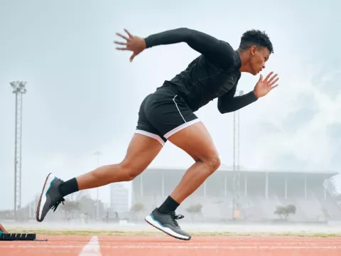 A Male Athlete Jumps Out of the Starting Blocks on a Track