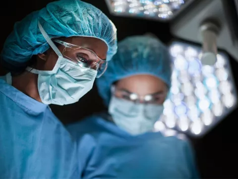 Surgeons Wearing Full Scrubs and Masks Operate on an Unseen Patient