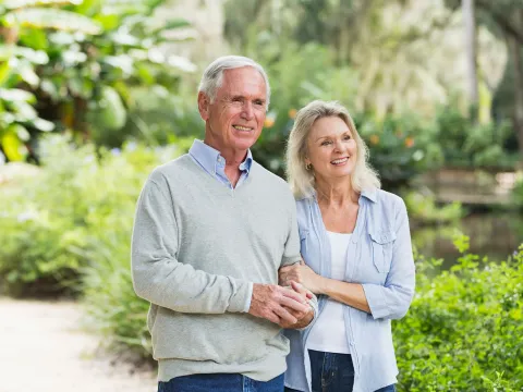 Senior Couple walking past several green shrubs and plants