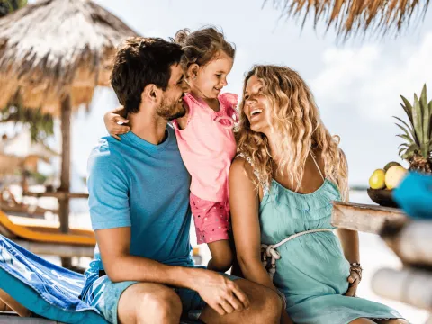 Family smiling at each other at beach.