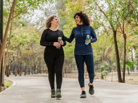 Two women walking on a trail outdoors.