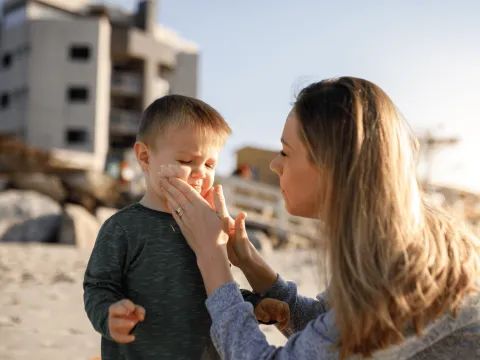 Mother putting sunscreen on chiild