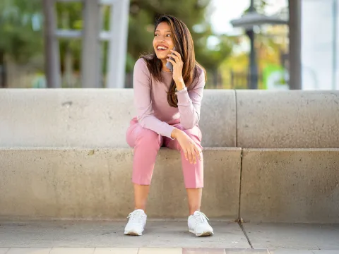 A Woman Chats on a Cell Phone Outside While Sitting in a Park