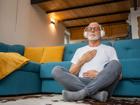 An older man meditating at home.