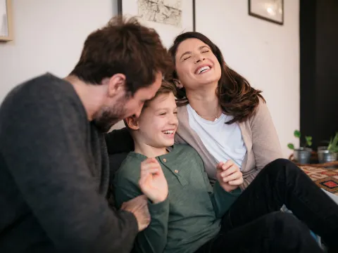 A happy young family sitting on a couch in the living room.