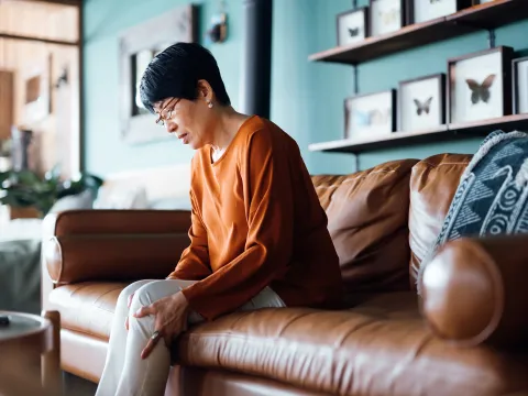 Woman Sitting on her couch clutching her leg with pain