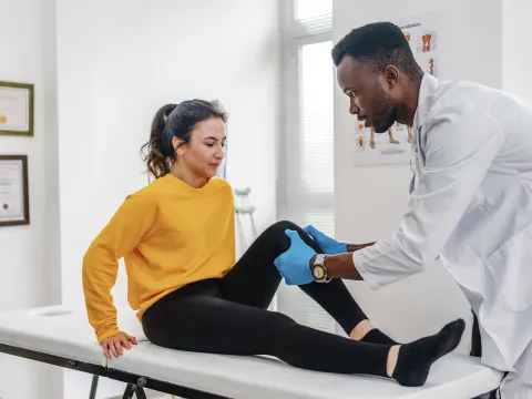 Doctor examining female patient's leg