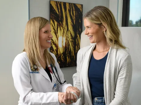 Female doctor holding female patient's hand and smiling