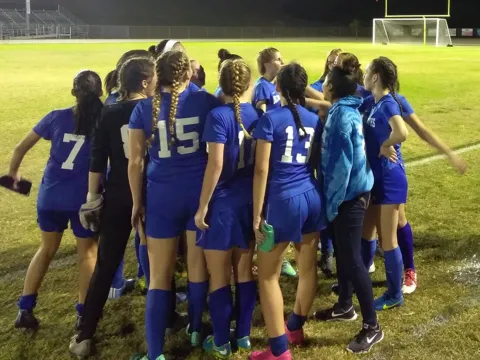 Girls soccer team in a huddle.