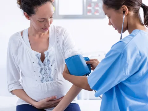 Pregnant woman gets her blood pressure checked at the doctor.