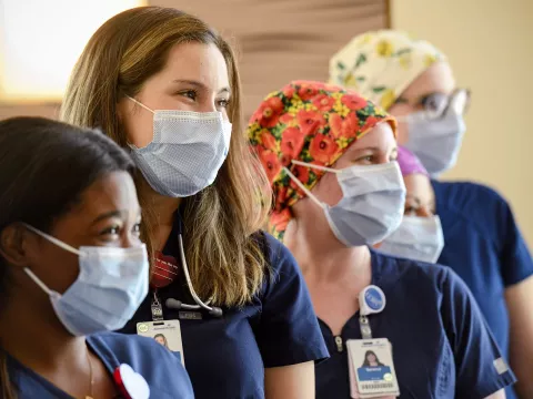 Four masked nurses smiling, diversity