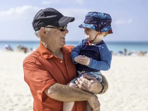 A grandfather and grandson practice sun safety at the beach.