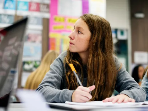 A Teen Student Sits in a Class Taking Notes
