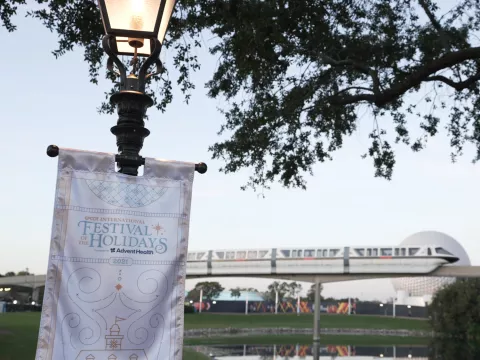 Epcot International Festival of the Holidays banner with monorail and Spaceship Earth in the background.
