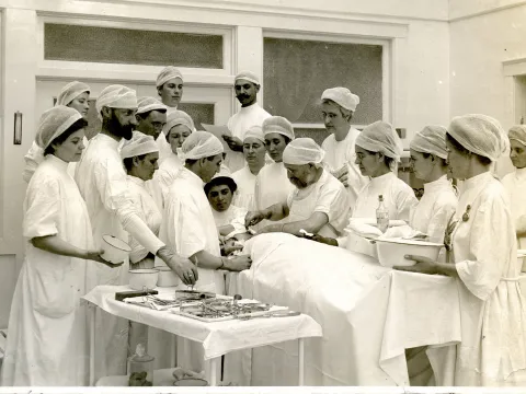 John Harvey Kellogg performing surgery with surgical team and viewers.