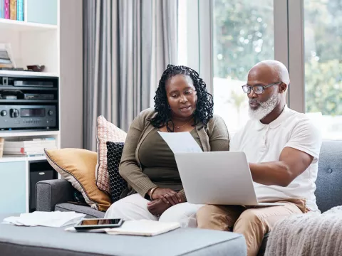 Man and woman reviewing paperwork with computer on lap