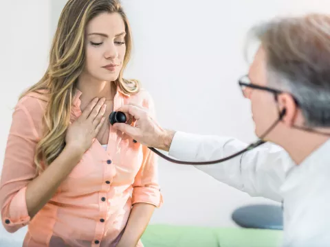 A doctor checking a woman's heart beat