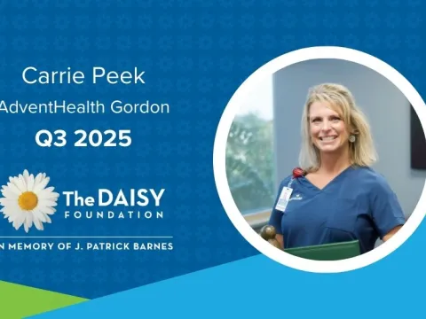 Carrie Peek, a white, blonde woman wearing blue scrubs, stands with her DAISY Award certificate and statue.