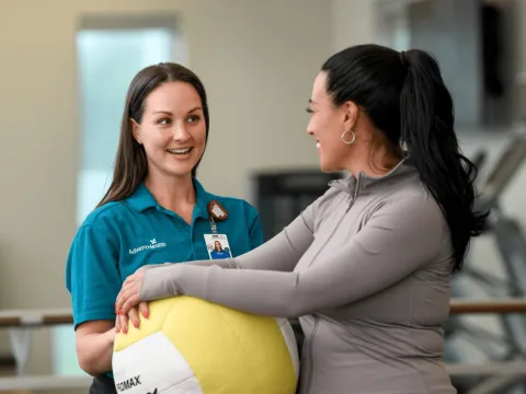 AdventHealth physician talking to patient holding yellow excercise ball
