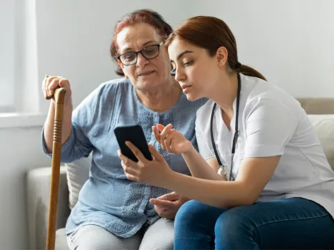 Doctor showing a senior woman something on a smart phone.