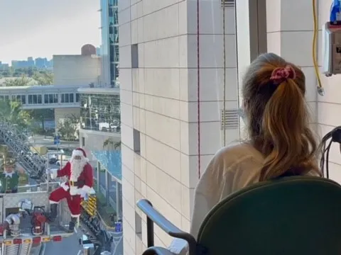 A young patient spots Santa outside her window at AdventHealth for Children. 