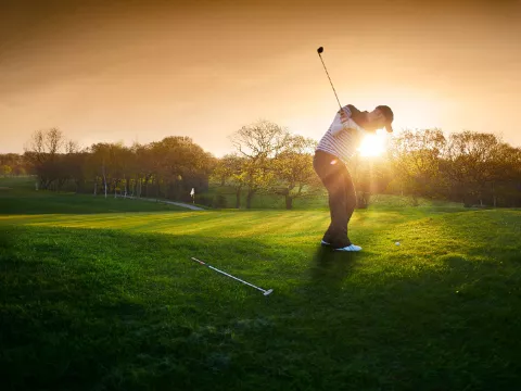 A golfer playing during sunrise
