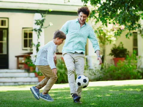 Father and son playing soccer.