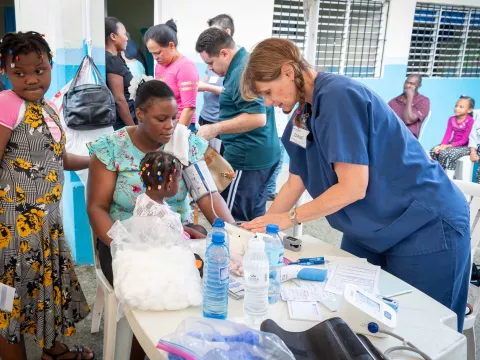 Doctor checking woman's blood pressure while her children are near here.