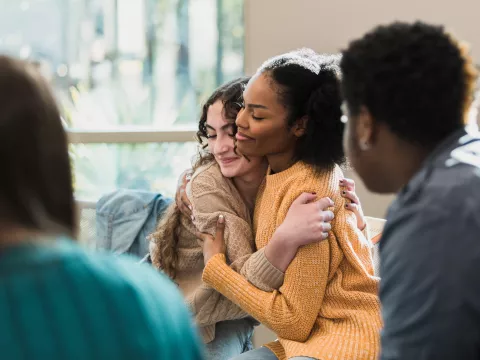 Two Women Happily Embrace After a Group Discussion