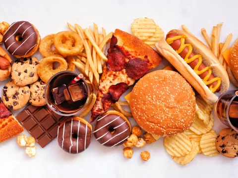 Collection of junk foods scattered over a white marble background