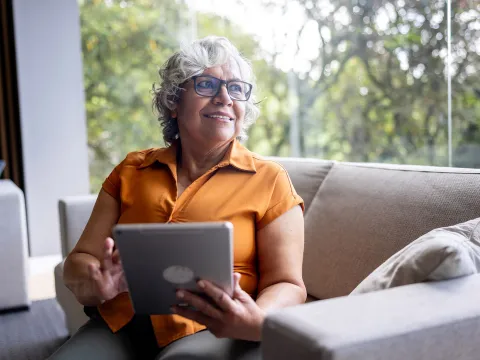 An older woman holding a tablet.