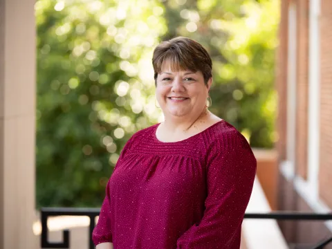 Laurie Chandler, a white woman with short brown hair and wearing a burgundy top, smiles at the camera.  The background appears to be a blurred, outdoor porch setting.