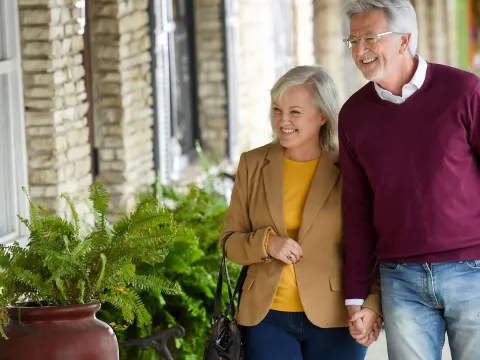 A couple of seniors holding hands while walking outdoors