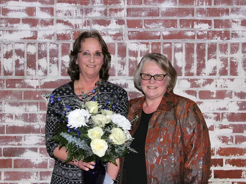 Two women receiving a flower arrangement.
