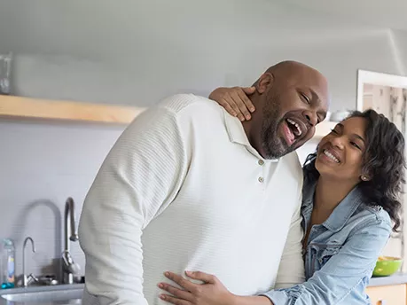A couple hugging each other while cooking on the kitchen