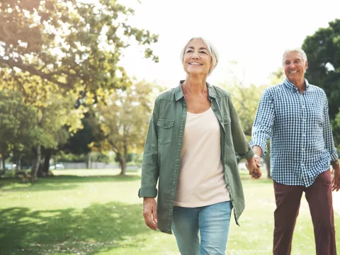 Elderly couple holding hands and walking in a park