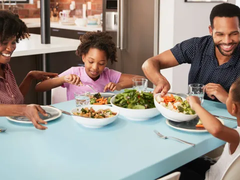 A young family sits down at the table to eat lunch