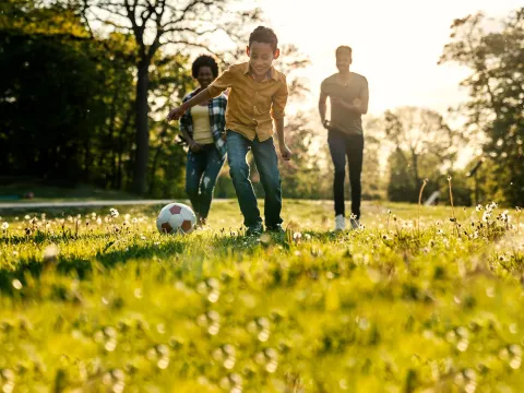 A family playing soccer together outdoors.
