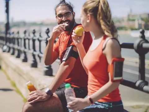 Two runners eat a healthy snack.