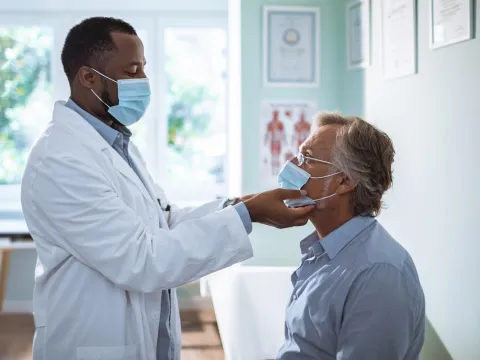 A Doctor Examines a Patient's Throat While Taking Vitals