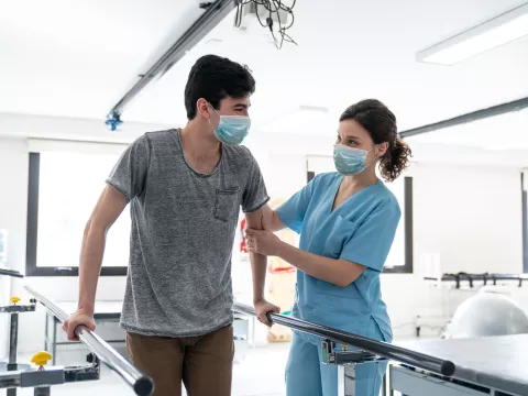 A man with a female nurse as they go through a session of physical rehab.