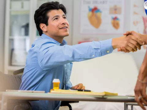 A man shakes the hand of a new doctor.