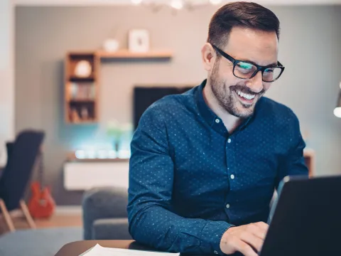 A man indoors and on his laptop