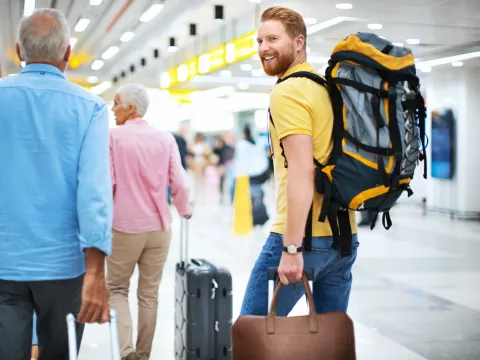 A man wearing a backpack at the airport.