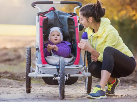A new mom takes a water break during a run with her baby.