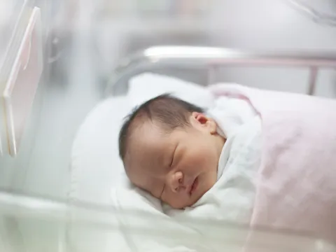 A newborn rests in her bed in the delivery room