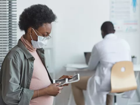 A pregnant woman looking at lab results in her doctor's office