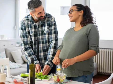 A pregnant woman and her husband make a healthy meal.