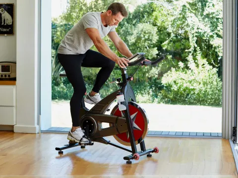 A man riding an exercise bike at home.